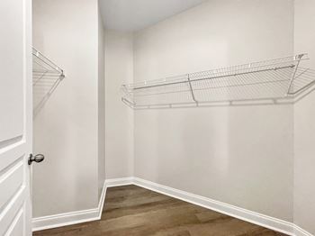 A white closet with a door and shelves.
